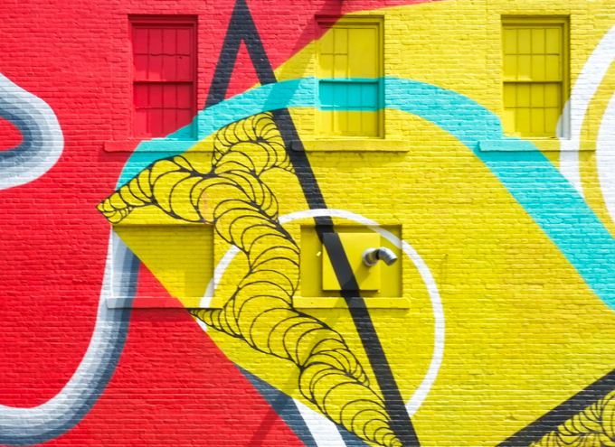 close up of Kim Carlino mural in red and yellow, painted over windows, white black and turquoise lines run through the red and yellow parts. 