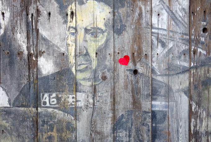 mural, faded, portrait of a man, with a small red heart sticker on it, 