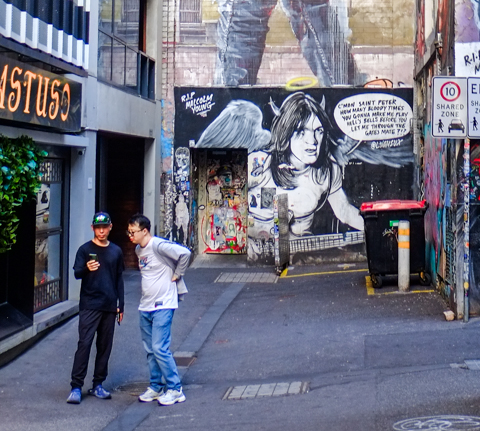 street art in ACDC lane, central Melbourne, two men taking selfies in front of musician portrait with devil horns and angel wings