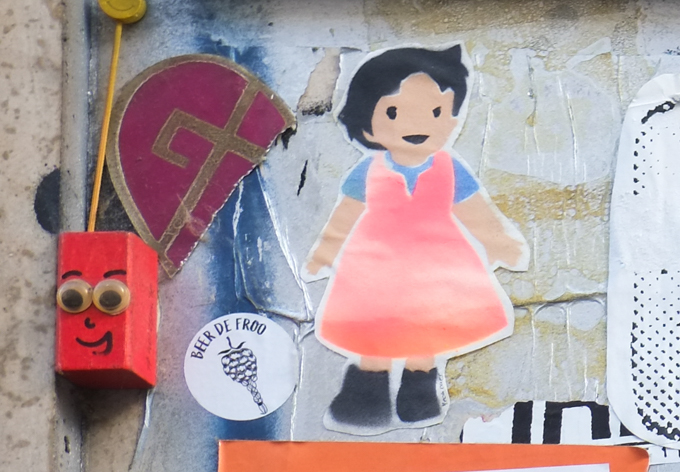 pasteups on a wall in Cologne, little girl in orange dress, beer de froo, small red block with googly eyes