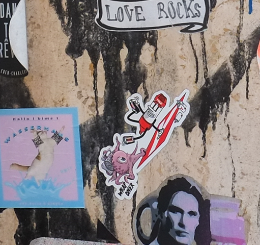 pasteups on a wall in Cologne or Koln, love rocks, a black and white portrait of a man, 