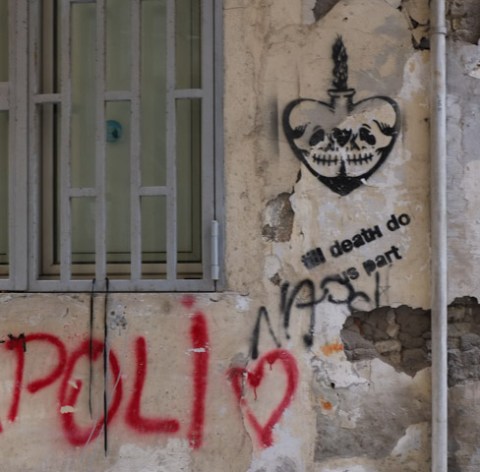 black graffiti on grey wall, a drawing of a heart with face in it so that it looks a bit like a skull, with text that says til death do us part 