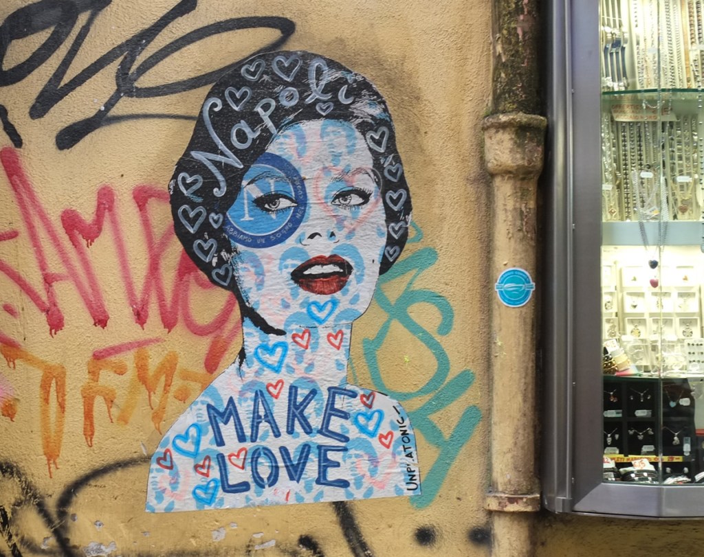 paste up graffiti by unplatonic, woman's face with hearts, the word Napoli, and the words make love