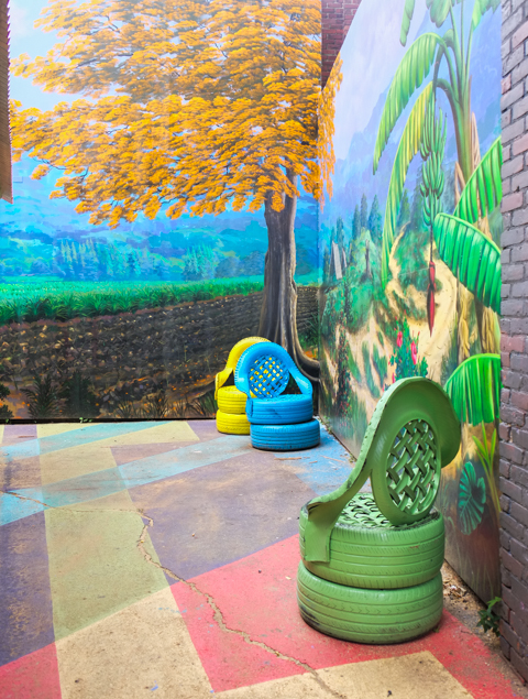 outdoor chairs on a patio, with murals on the walls behind them 