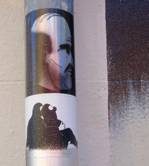 two graffiti stickers on a pole
