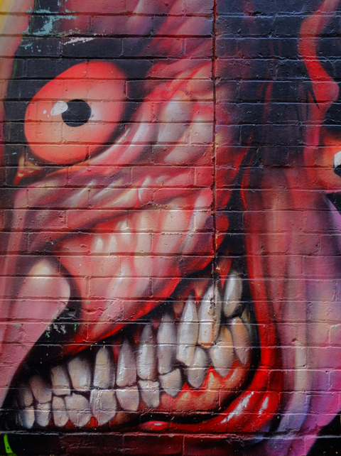 very close up of face of Joker with big teeth muscles, mural by Heesco 