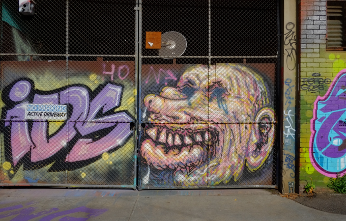 ugly mis-shapen face painted on gate, small forehead, large jaw, mouth and teeth, long nose, 