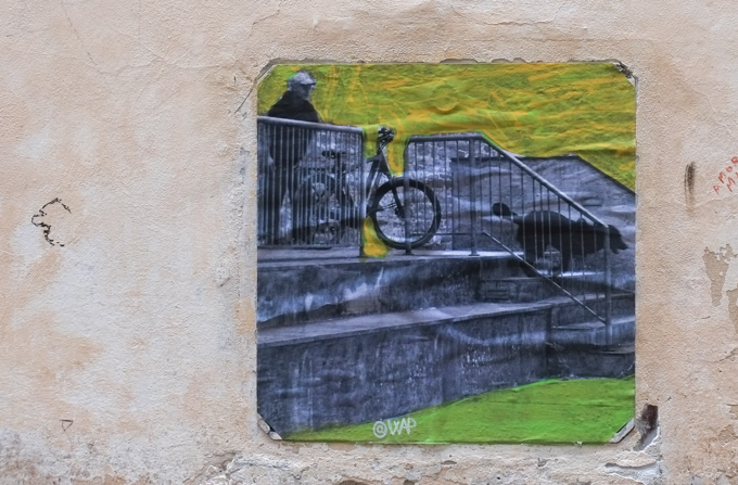 graffiti paste up made from black and white photo of a man on a bicycle and his dog, going down stairs outside