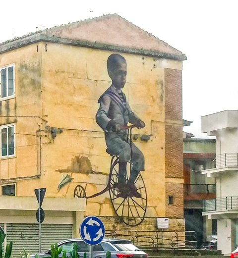 mural of boy in old fashioned clothes on old fashioned bicycle