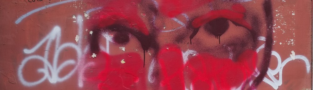 close up a graffiti painting of a very red face with black eyes