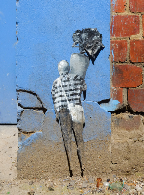 graffiti pasteup, man from back, wearing plaid shirt, carrying white over the shoulder bag,, also carrying very large gigantic carrot.