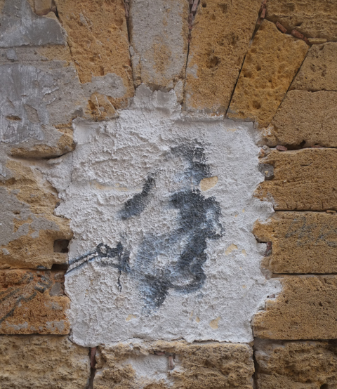 faded street art on an old brick and stone wall, textures, alley in Palermo