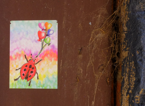 graffiti, ladybug holding a bunch of helium filled balloons