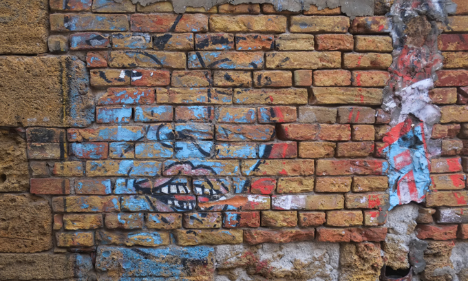 faded street art on an old brick and stone wall, textures, alley in Palermo