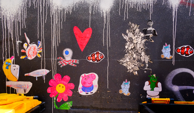 collection of graffiti stickers and paste ups on a wall