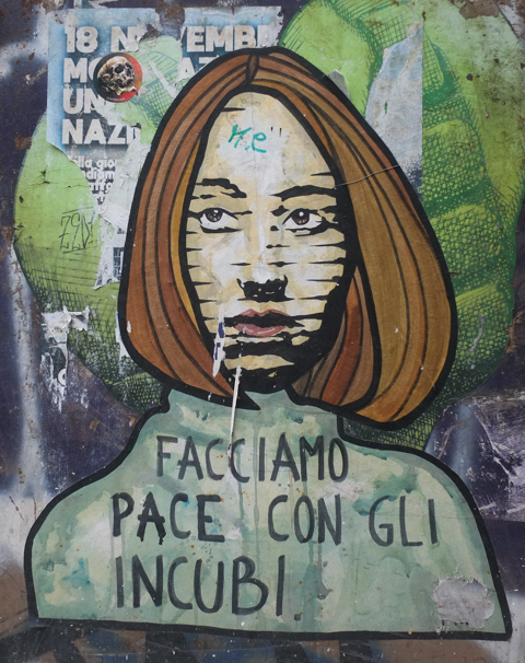 portrait of woman with shoulder length brown hair and green top, with text in italian, facciamo pace con gli incubi which translates to let's make peace with this nightmare