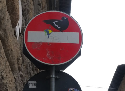 modified traffic sign, graffiti, by Clet Abraham, in Florence, bird crapping on white bar