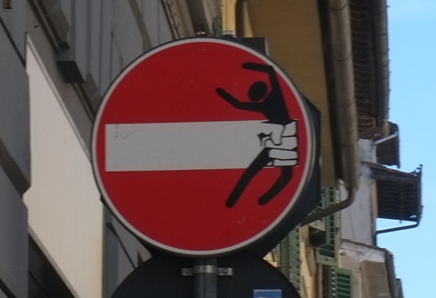 modified traffic sign, graffiti, by Clet Abraham, in Florence, black figure being held back