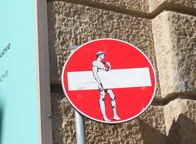 modified traffic sign, graffiti, by Clet Abraham, in Florence, white bar is modesty for Michaelangelo's David statue