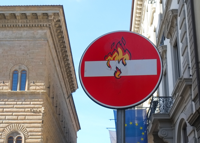 modified traffic sign, graffiti, by Clet Abraham, in Florence, fire and flames