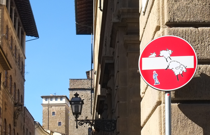modified traffic sign, graffiti, by Clet Abraham, in Florence, sheep jumping over white bar