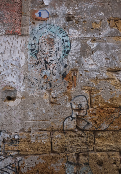 faded street art on an old brick and stone wall, textures, alley in Palermo