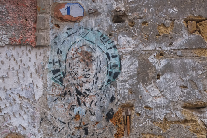 faded street art on an old brick and stone wall, textures, alley in Palermo