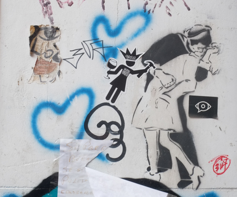 stencil graffiti, a couple kissing, a figure holding a hammer and a glass of red wine