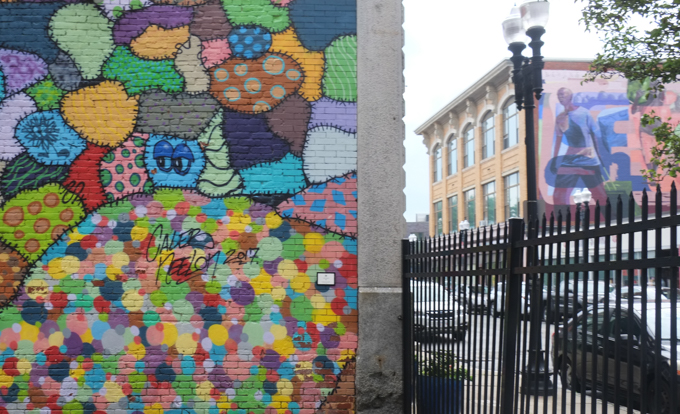 edge of mural by Caleb Neelon in Lynn Massachusetts, beside wrought iton fence, with another mural in the background