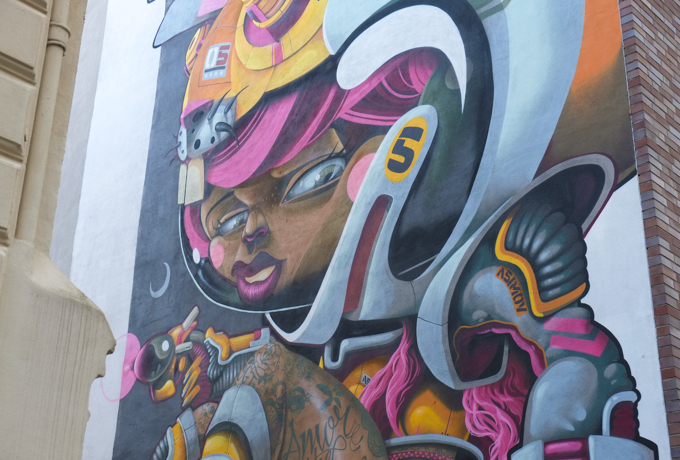 large mural in Nippes Cologne, by Danjer Mola, of a female astronaut with either bare legs or brown skin tight leggings