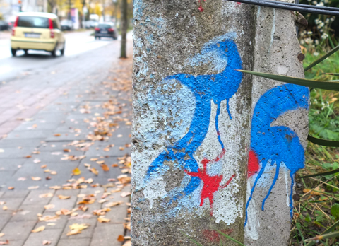 small street art painting on the end of a concrete wall beside a garden