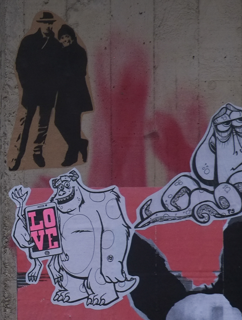 paste ups, graffiti, featuring Sulley from the movie "Monsters Inc". holding a phone that says love, also an image of a couple standing together