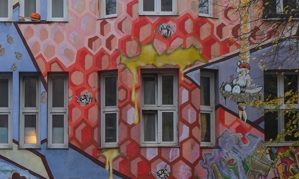 residential building on kiefernstrasse covered with street art that looks like a large red honeycomb