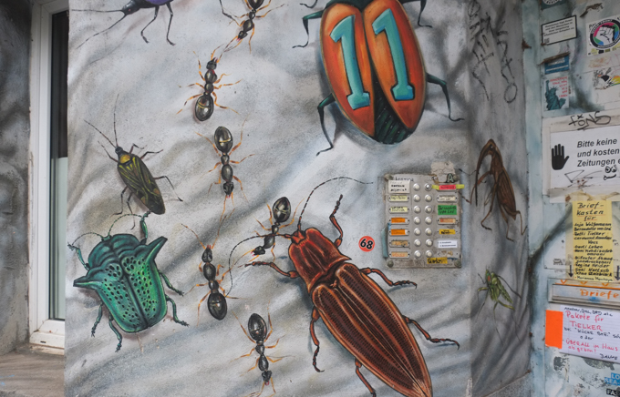 4 storey residential building covered in paintings of insects,  cockroaches, beetles, ants, and others both real and imaginary, mural in Dusseldorf, some insects have human faces