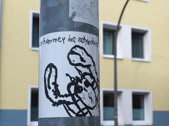 sticker on a pole that seems to say dey hummey des schrecken but that doesn't translate into english
