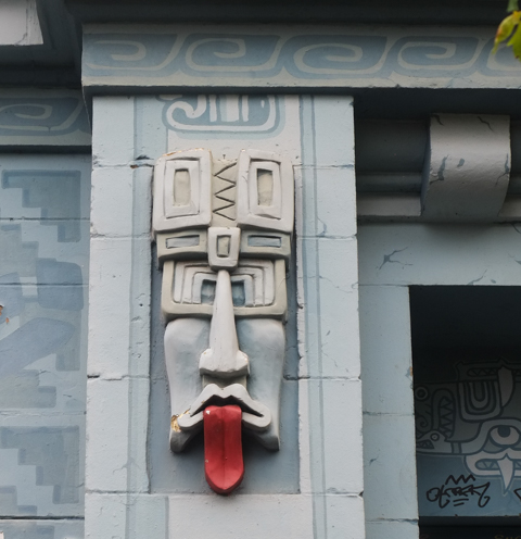 addition of a long red tongue to fake stonework on the front of a building, on a face with big nose and square eyes