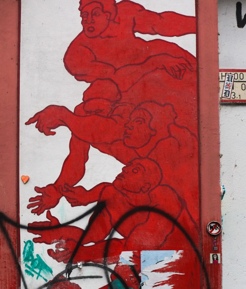 painting on a door, in reds, 4 people reaching 