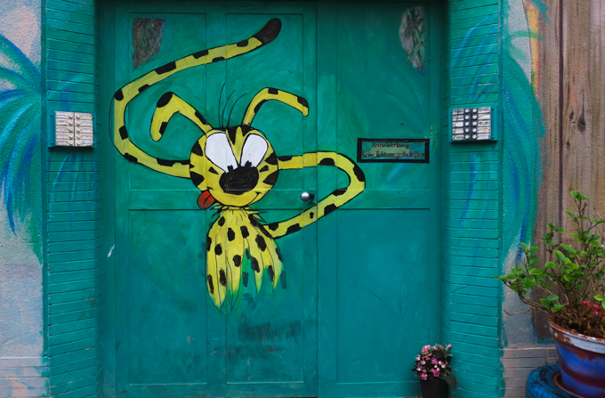 marsupilami painting on a green door, a yellow animal with black spots