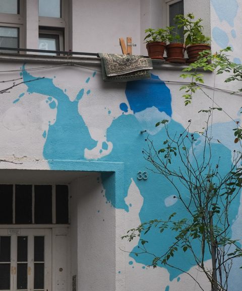 building with potted plants on the balcony, and walls white with big blue splotches