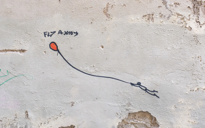 graffiti in Florence Italy by artist Exitenter, black drawing of a person holding onto a string that is attached to a red balloon.   balloon is flying away, taking person with it.  text says fly away