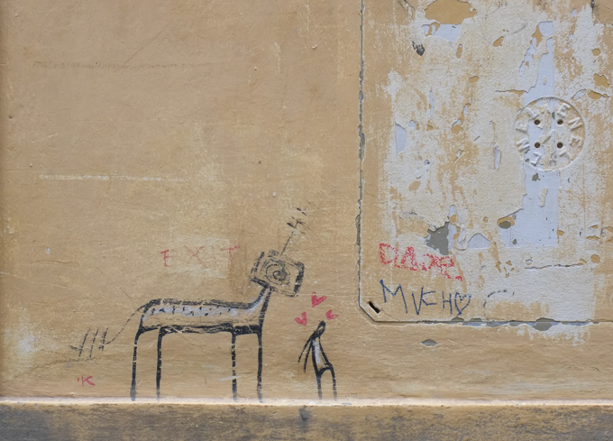 graffiti in Florence Italy by artist Exitenter, black drawing of a person standing with his back to a horse.  three small hearts above man's head, head of horse is a television (could be a very large dog not a horse)