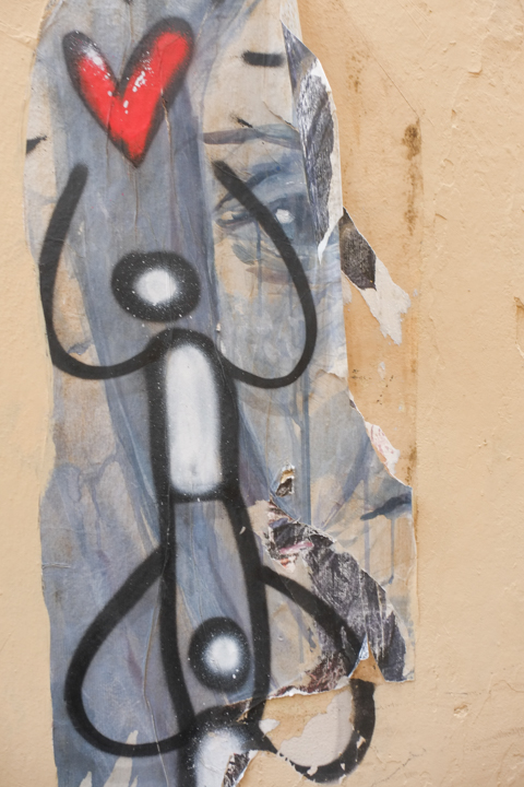 graffiti in Florence Italy by artist Exitenter, black drawing of two people, one standing on the shoulders of the other while reaching for a red heart