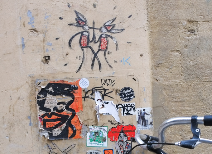 graffiti in Florence Italy by artist Exitenter, black drawing of two people  wearing red and white hats, sword fighting 