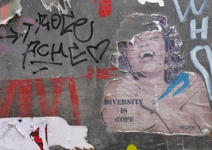 large paper wheatpaste on a door, black woman with arms crossed to her shoulders, laughing, with text diversity is hope, by RAF Union