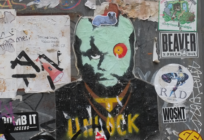 graffiti including one by cartoon car slaps of a green car, a pink light, a dog, a man with a green face, the word unlock, 