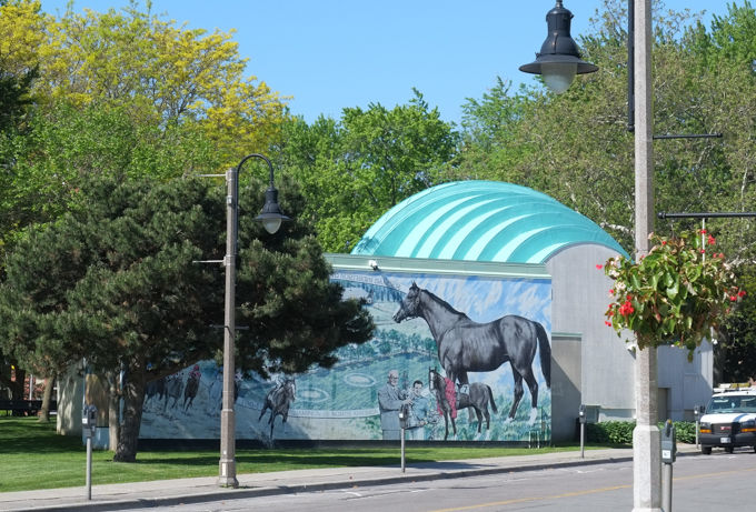 on the exterior of the bandshell in memorial park, mural by David Yeatman showing E. P. Taylor and the Windfelds Farm in Oshawa where famous racing thoroughbred horse Northern Dancer was born 