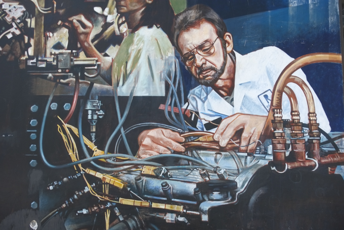 man working on a car engine, mural by John Hood