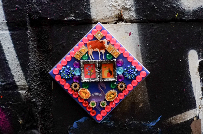 Diamond shaped graffiti piece, made with beads, includes a cow