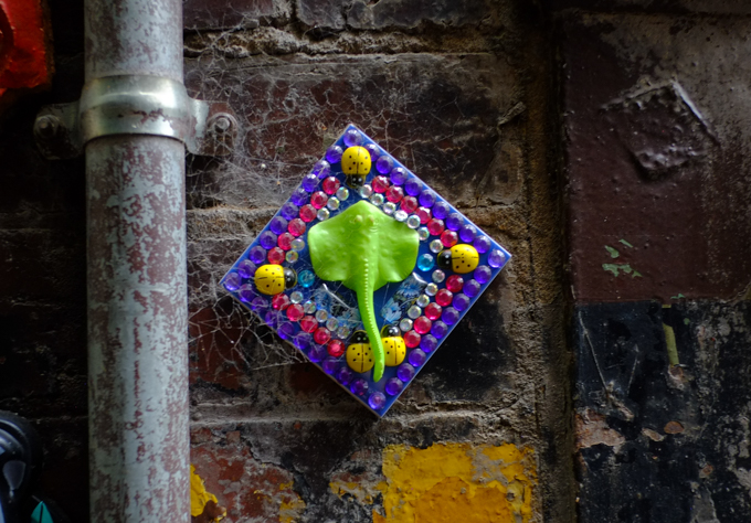 Diamond shaped graffiti piece, made with beads, includes a green manta ray in the center