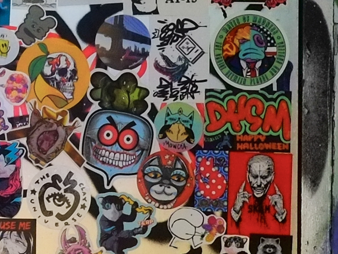 stickers on a windsor wall, including skull, tweet street art, and others